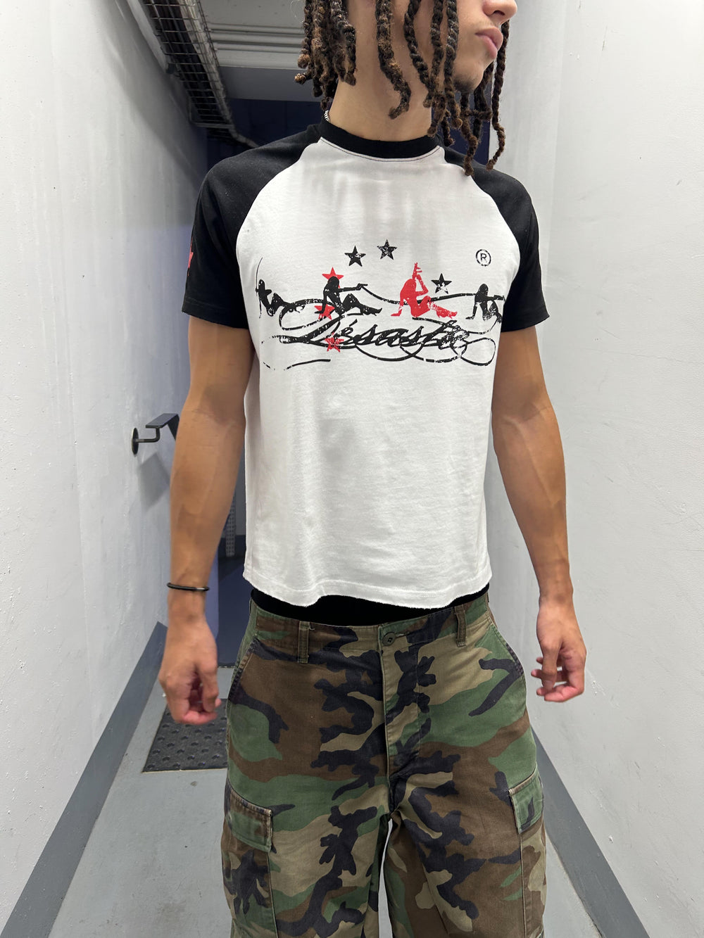 Désastre T-shirt porté avec un pantalon camouflage dans un couloir.